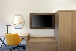 Une chambre moderne équipée d’un bureau, d’une chaise jaune, d’un téléviseur à écran plat et d’une armoire en bois.