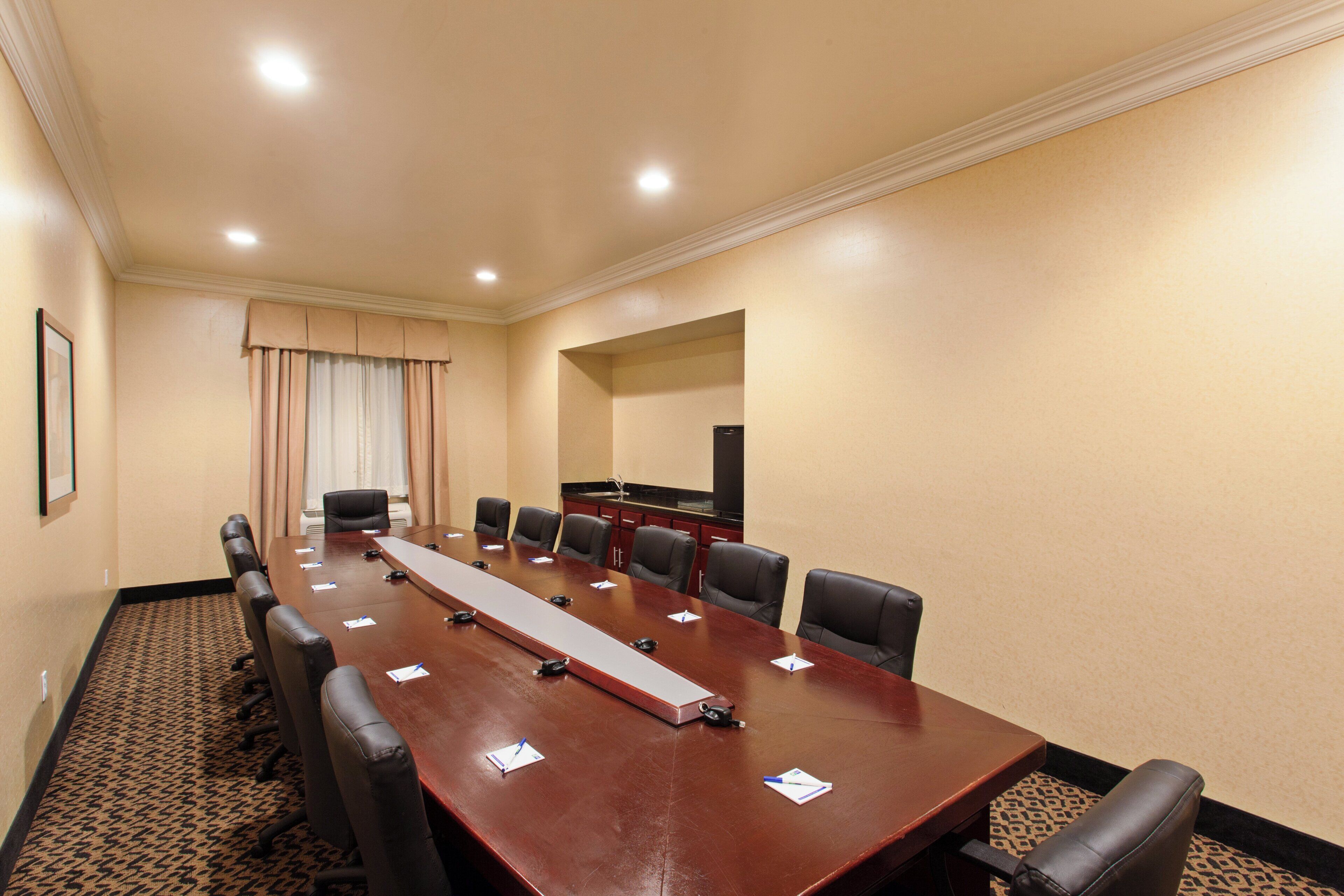 A conference room with a long table, chairs, a television, and a patterned carpet.