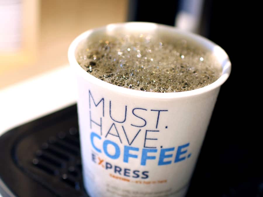 A coffee cup on a black tray with the text "MUST HAVE COFFEE EXPRESS".