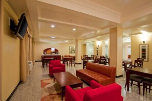 Un vestíbulo de hotel con zona de estar, mostrador de recepción y comedor.