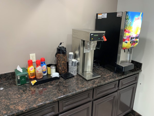 A coffee station with a coffee machine, a juice dispenser, and various beverage options. - Red Roof Inn Copiague (Copiague)