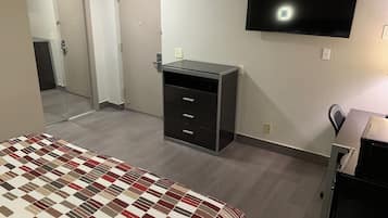 A hotel room with a bed, a dresser, a television, and a mirror.