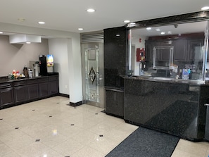 A modern hotel lobby with a reception desk, a coffee machine, and a refrigerator. - Red Roof Inn Copiague (Copiague)
