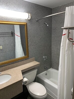 A bathroom with a toilet, sink, mirror, shower, and bathtub. - Red Roof Inn Copiague (Copiague)