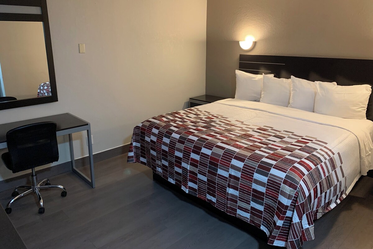 Una camera d'albergo con un letto, una scrivania, una sedia e un comodino.