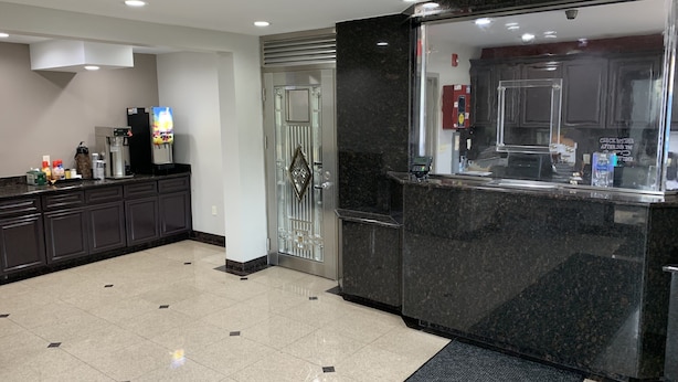A modern hotel lobby with a reception desk, a coffee machine, and a refrigerator.