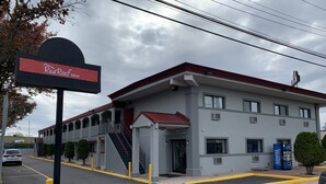 A Red Roof Inn with a modern design, featuring a red roof, multiple windows, and a parking lot with marked handicapped spaces.