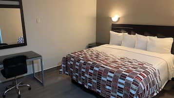 Ein Hotelzimmer mit Bett, Schreibtisch, Stuhl und Wandleuchte.