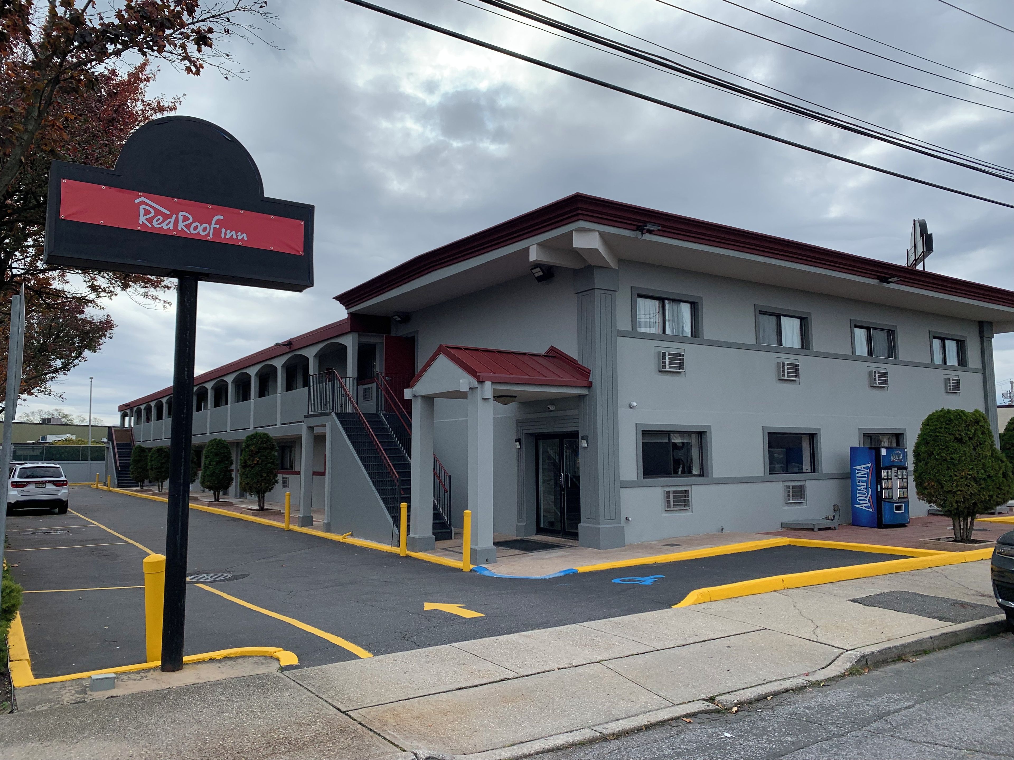 A Red Roof Inn with a modern design, featuring a red roof, multiple windows, and a parking lot with marked handicapped spaces.