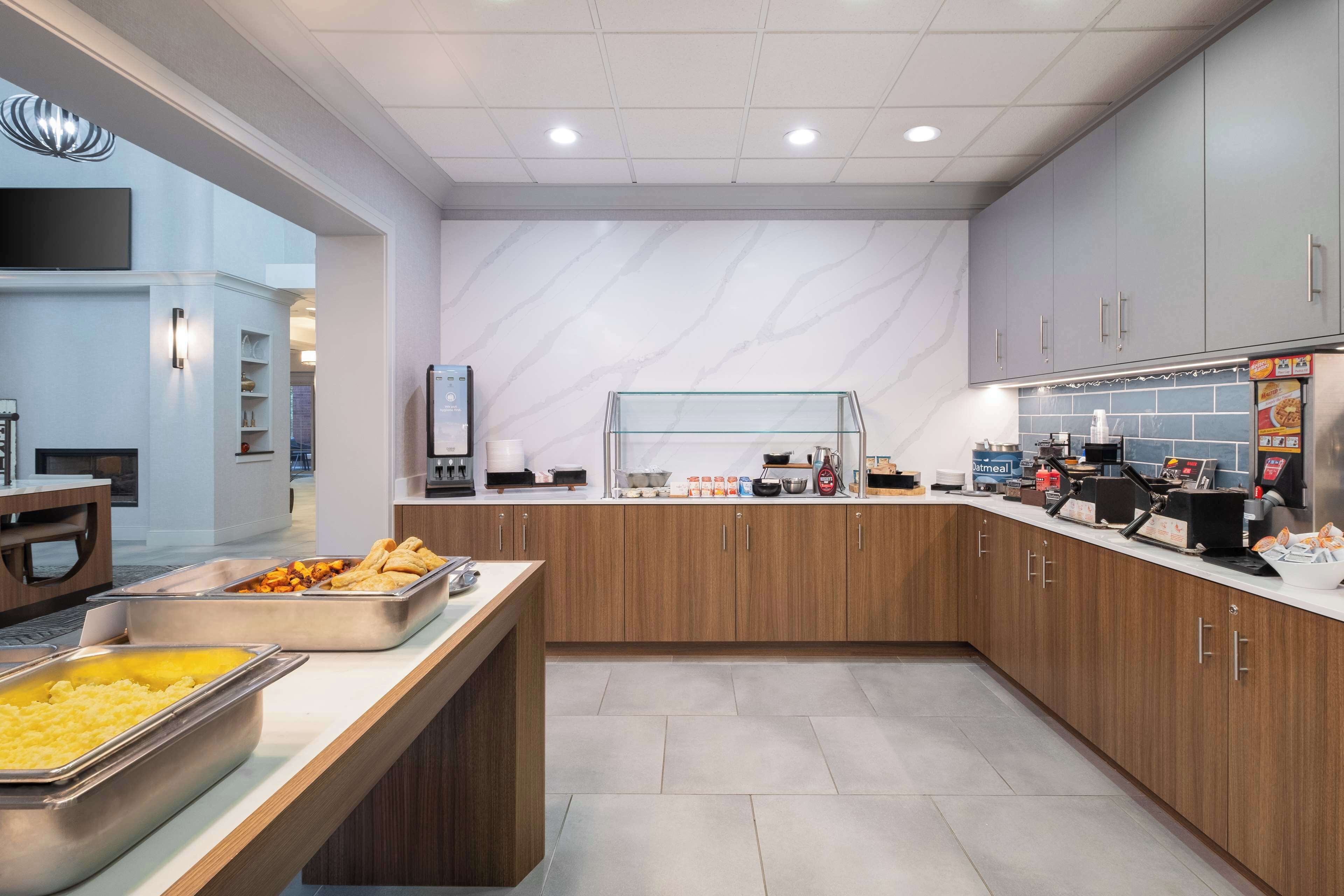 A modern kitchen with stainless steel appliances, a buffet counter with various food items, and a coffee station.