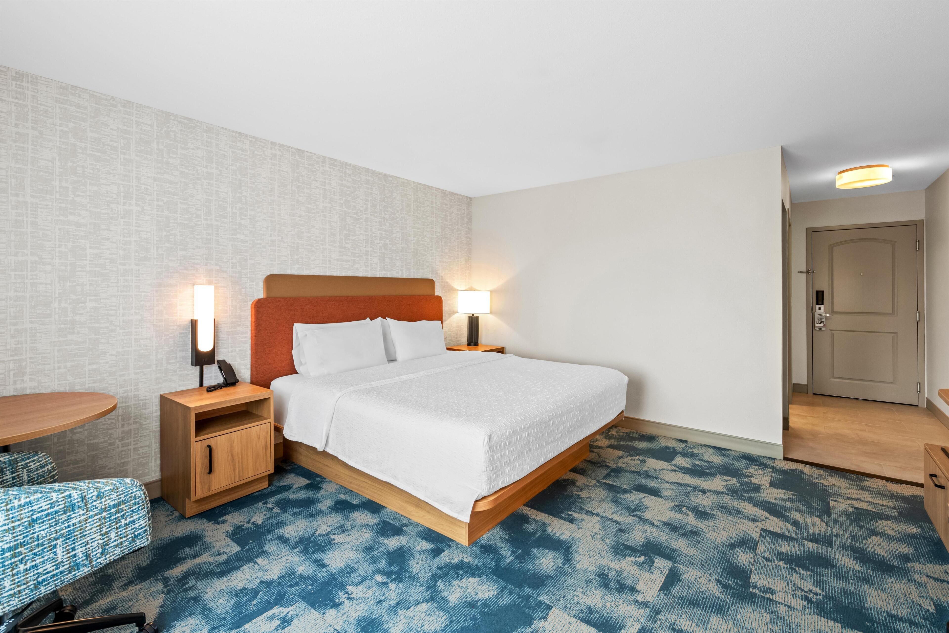 A hotel room with a bed, bedside tables, a desk, and a chair.