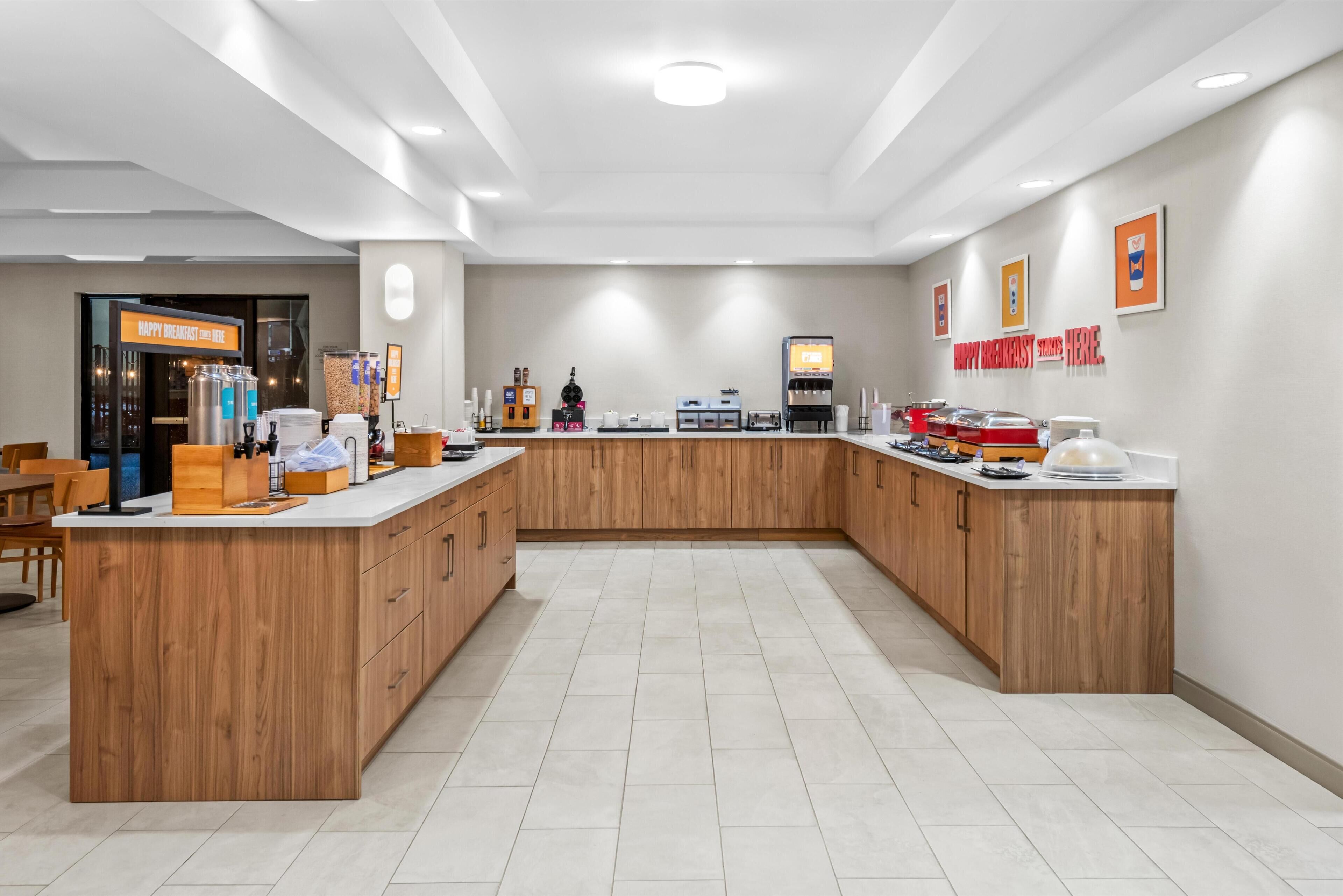 A modern kitchen with a central island, wooden cabinets, and a coffee station.