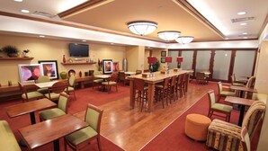 Un comedor de hotel con varias mesas y sillas, un televisor y adornos en las paredes.