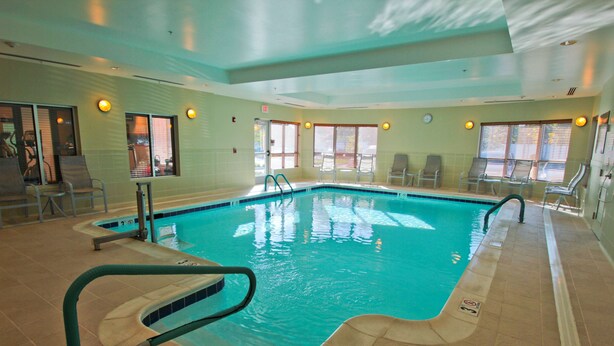 Una piscina interior con agua cristalina, rodeada de sillones de descanso y suelo de baldosas.