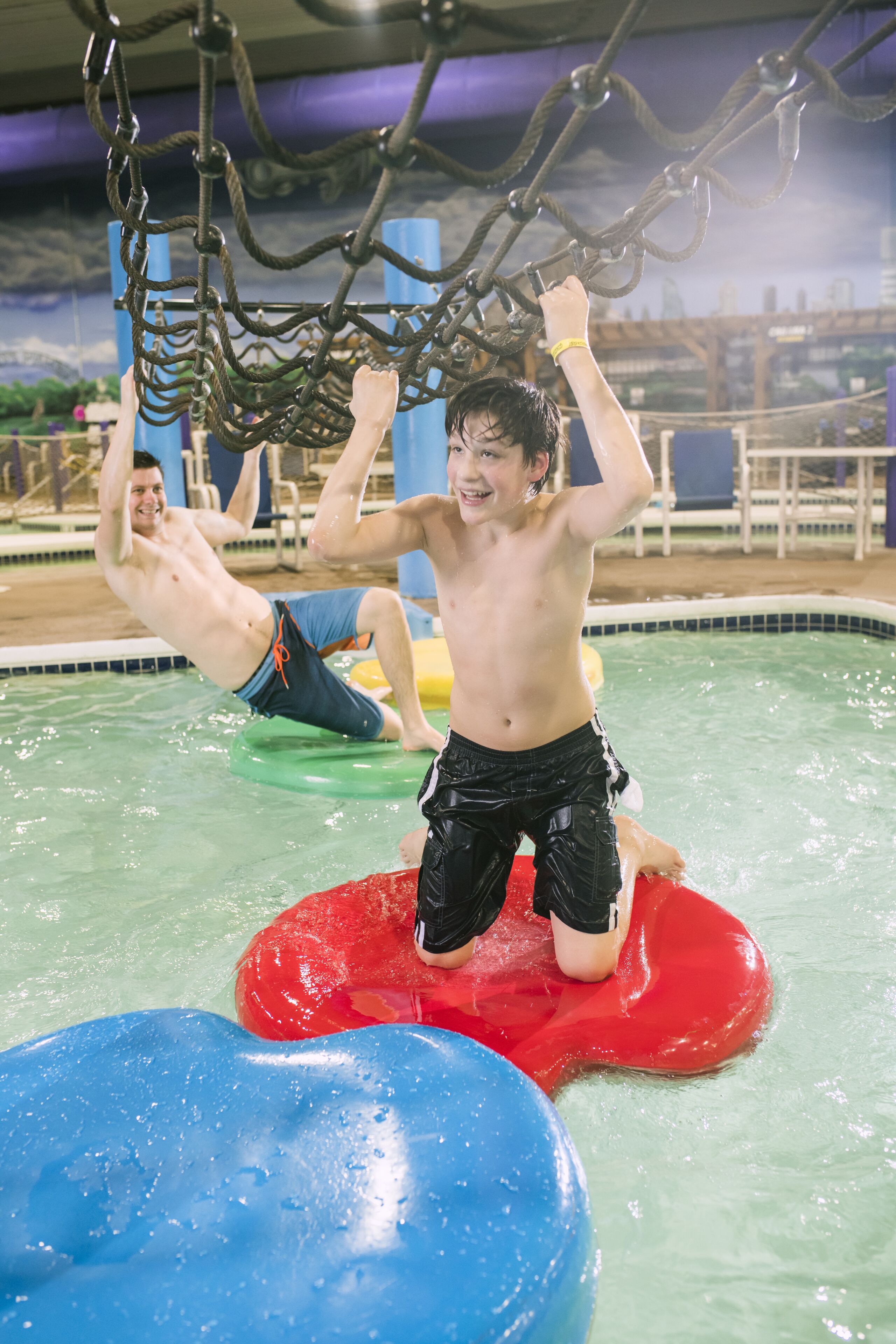 A pool area with ropes for climbing and floating devices.