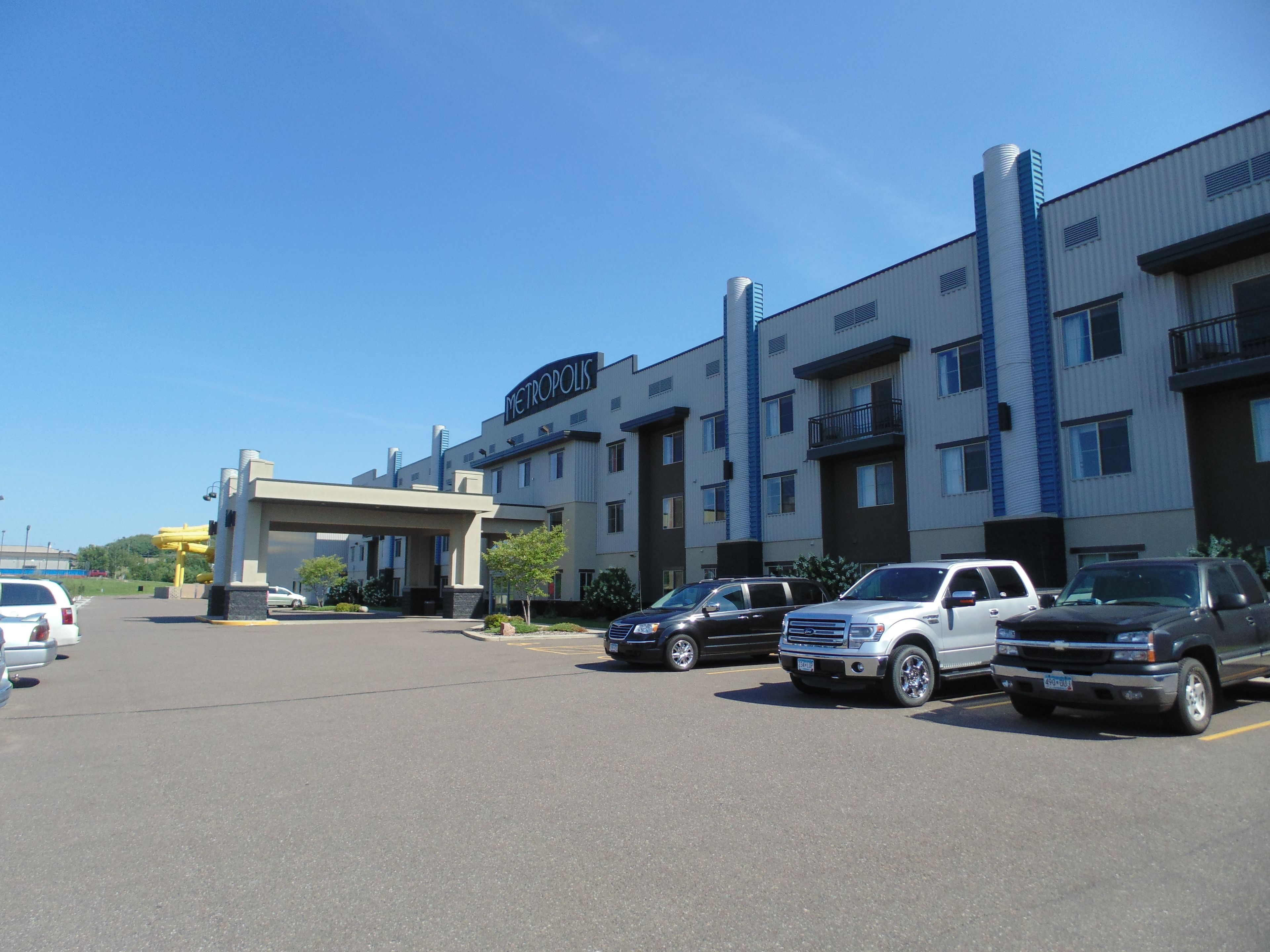 A parking lot with several vehicles, a building labeled "METROPOLIS," and a clear blue sky.