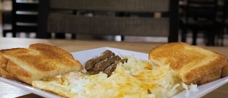 A plate of food with two slices of toast, a fried egg, and some meat on a white plate.