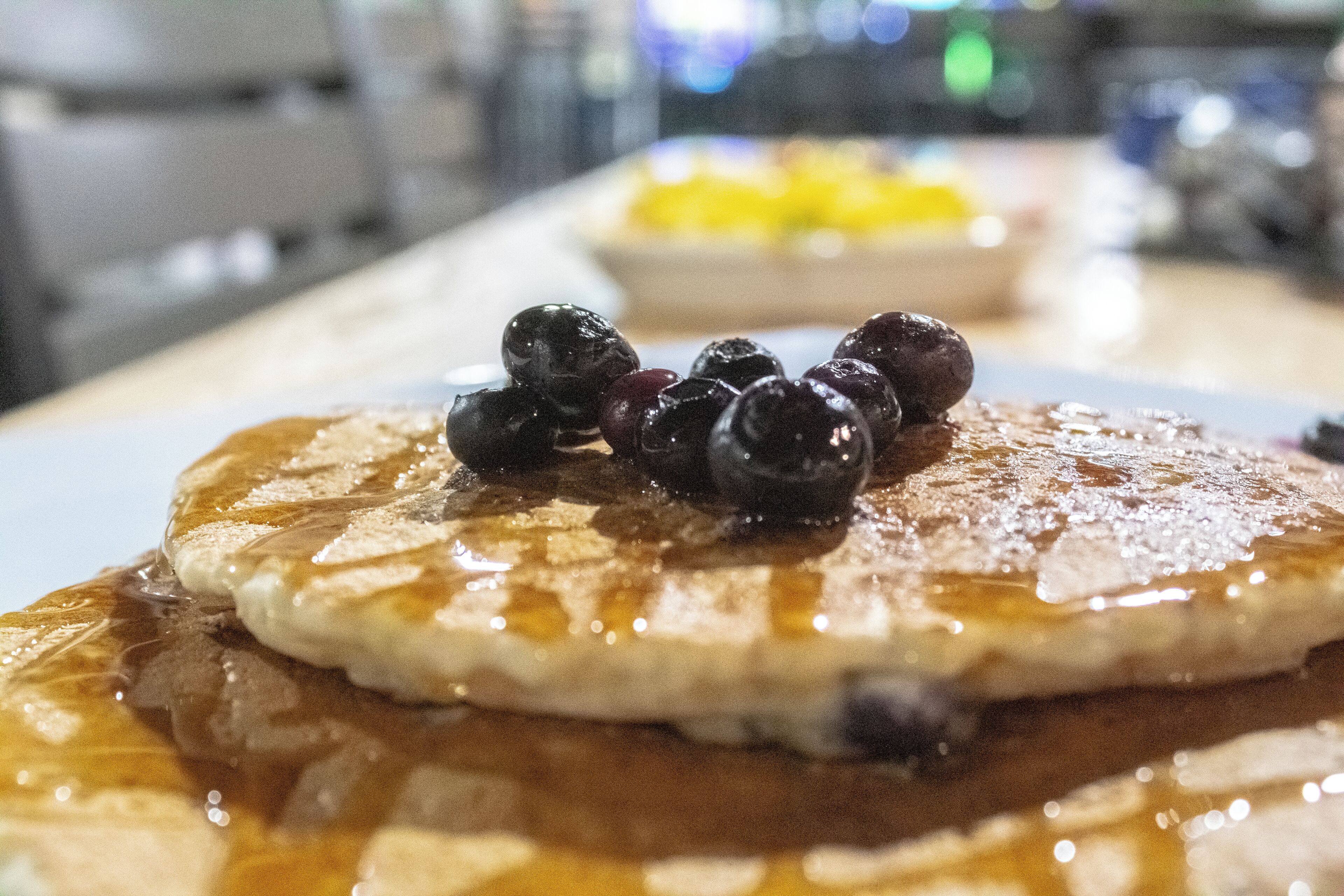 A stack of pancakes with syrup and blueberries on a plate.