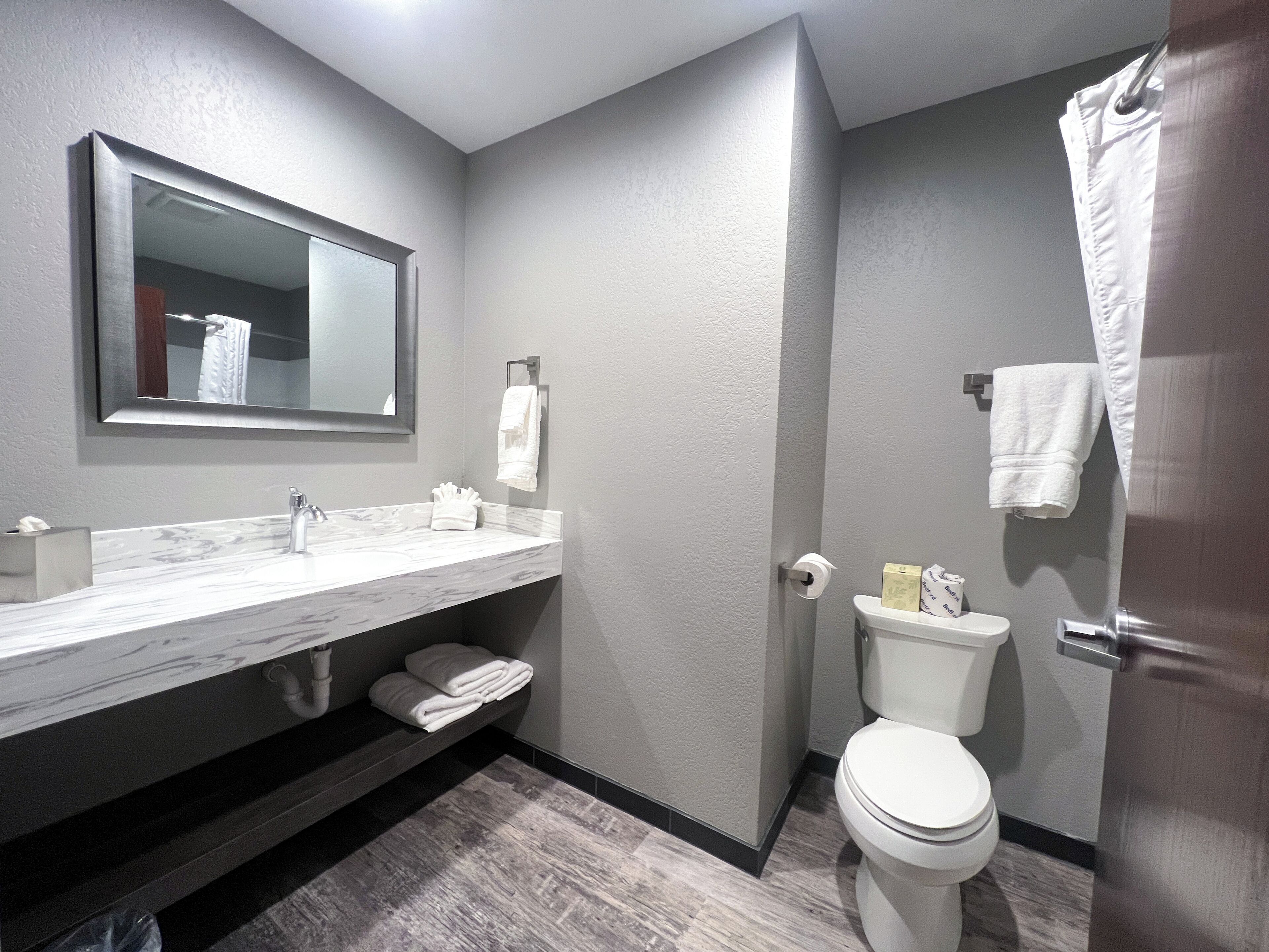 A modern bathroom with a marble sink, a toilet, and a shower curtain.