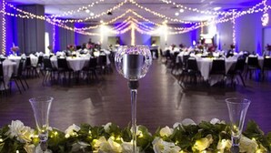 A banquet hall with tables set for a formal event, decorated with string lights and floral arrangements. - Metropolis Resort (Eau Claire)