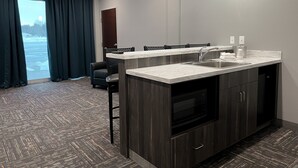A modern kitchen with a marble countertop, stainless steel sink, and dark wood cabinetry. - Metropolis Resort (Eau Claire)