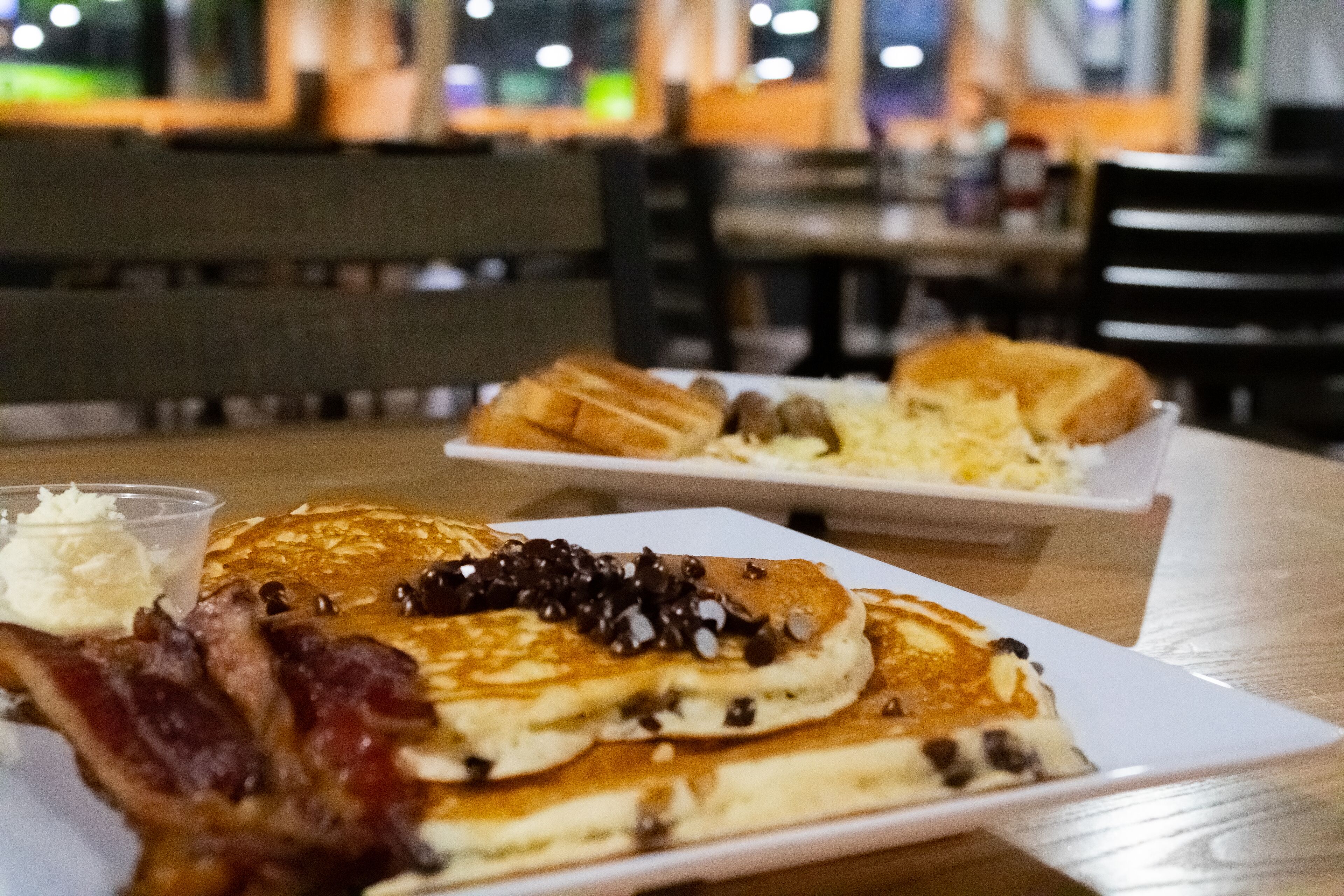 Desayuno con tortitas, tocino y gofres sobre una mesa.