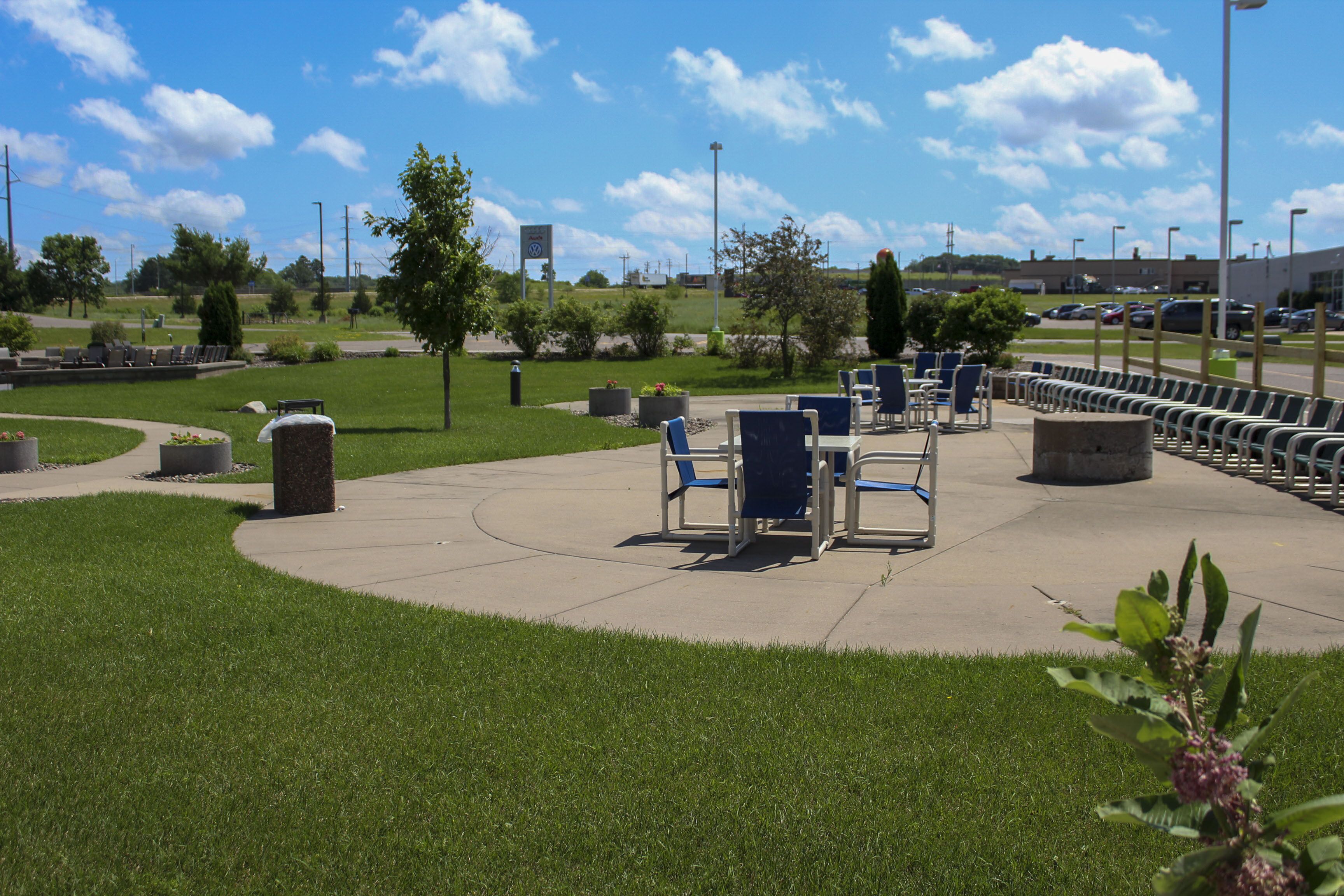 A park with outdoor seating and a parking lot.