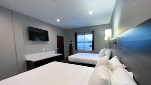 A hotel room with two beds, a TV, a window with a view of a parking lot, and a bathroom with a mirror and sink. - Metropolis Resort (Eau Claire)
