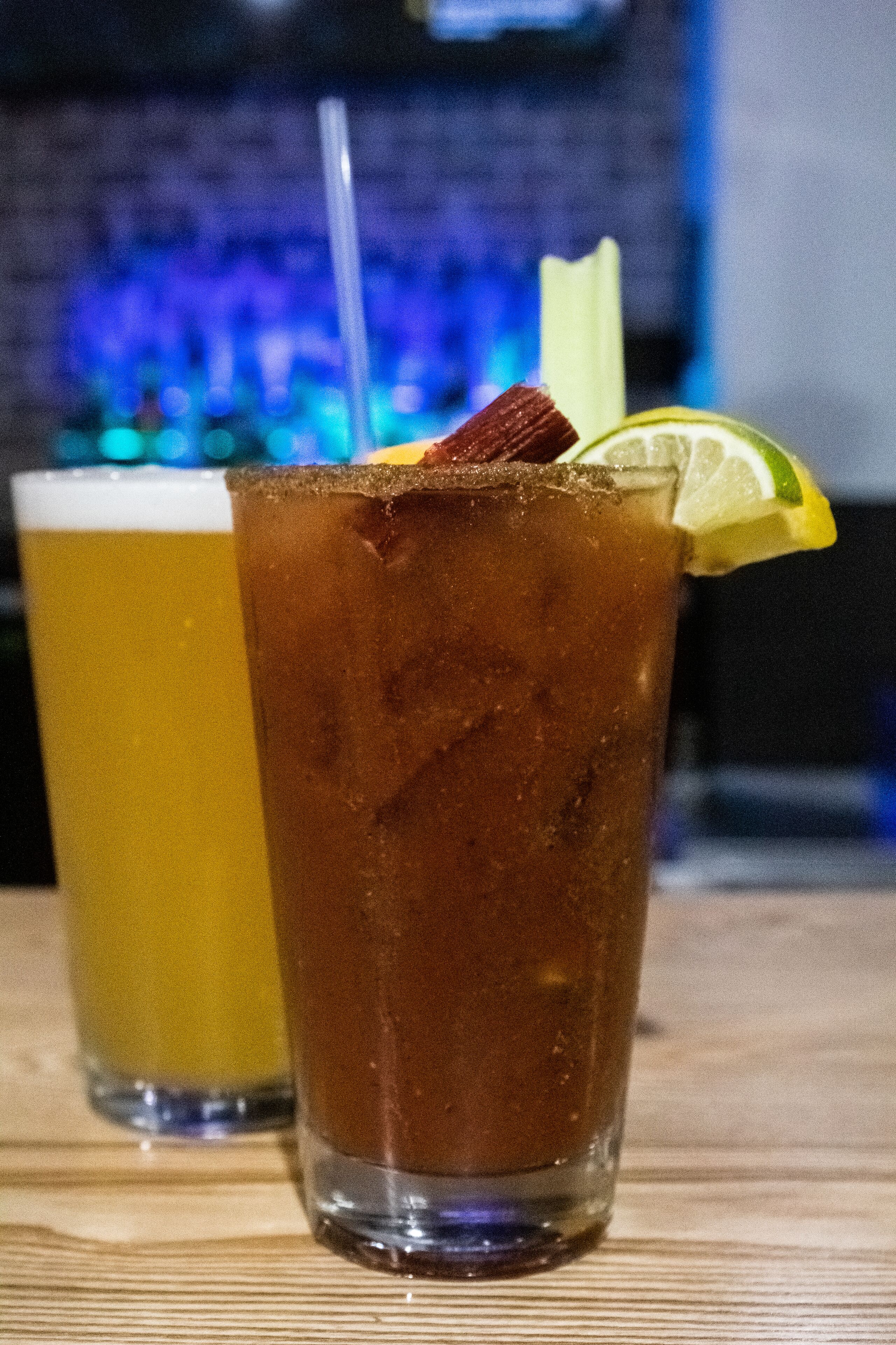 Dos vasos de bebidas heladas sobre una superficie de madera, con un fondo desenfocado.