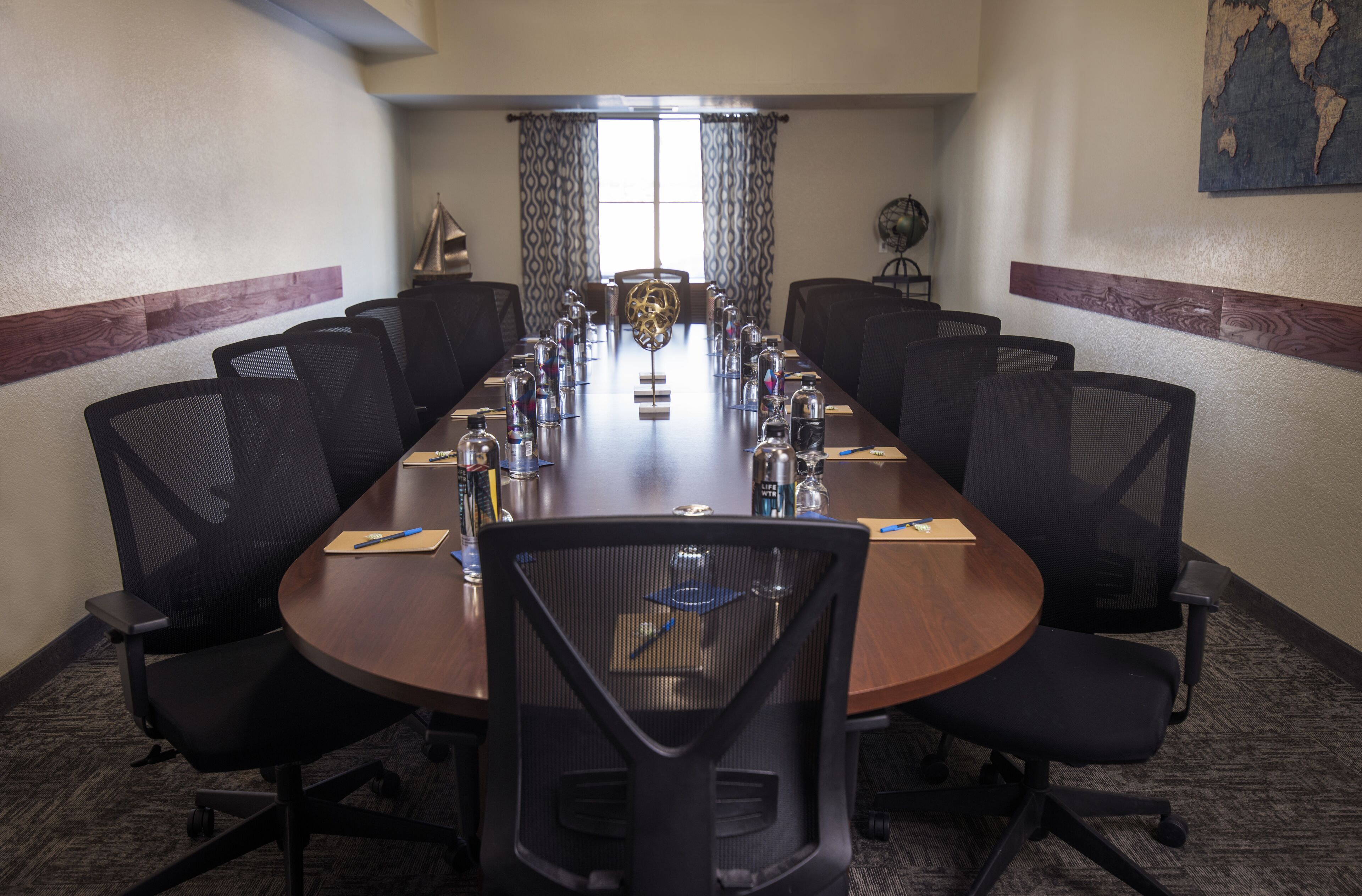 A conference room with a long table, black mesh chairs, and a globe centerpiece.