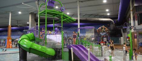 An indoor water park with slides, pools, and play structures.