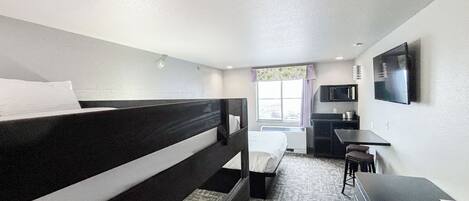 A hotel room with two single beds, a desk, a chair, a television, and a window with curtains.