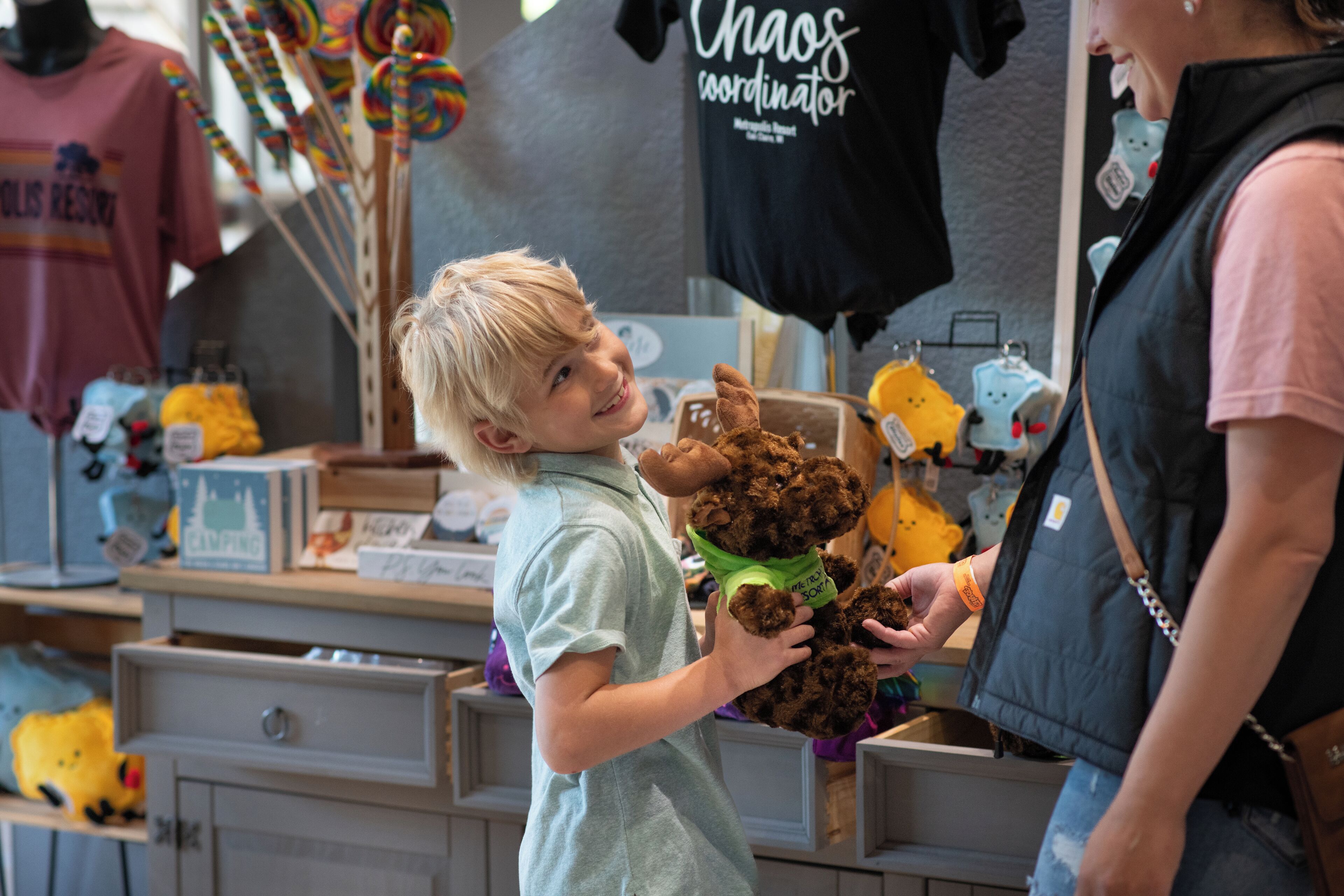 A child holding a stuffed animal at a store with various items on display.