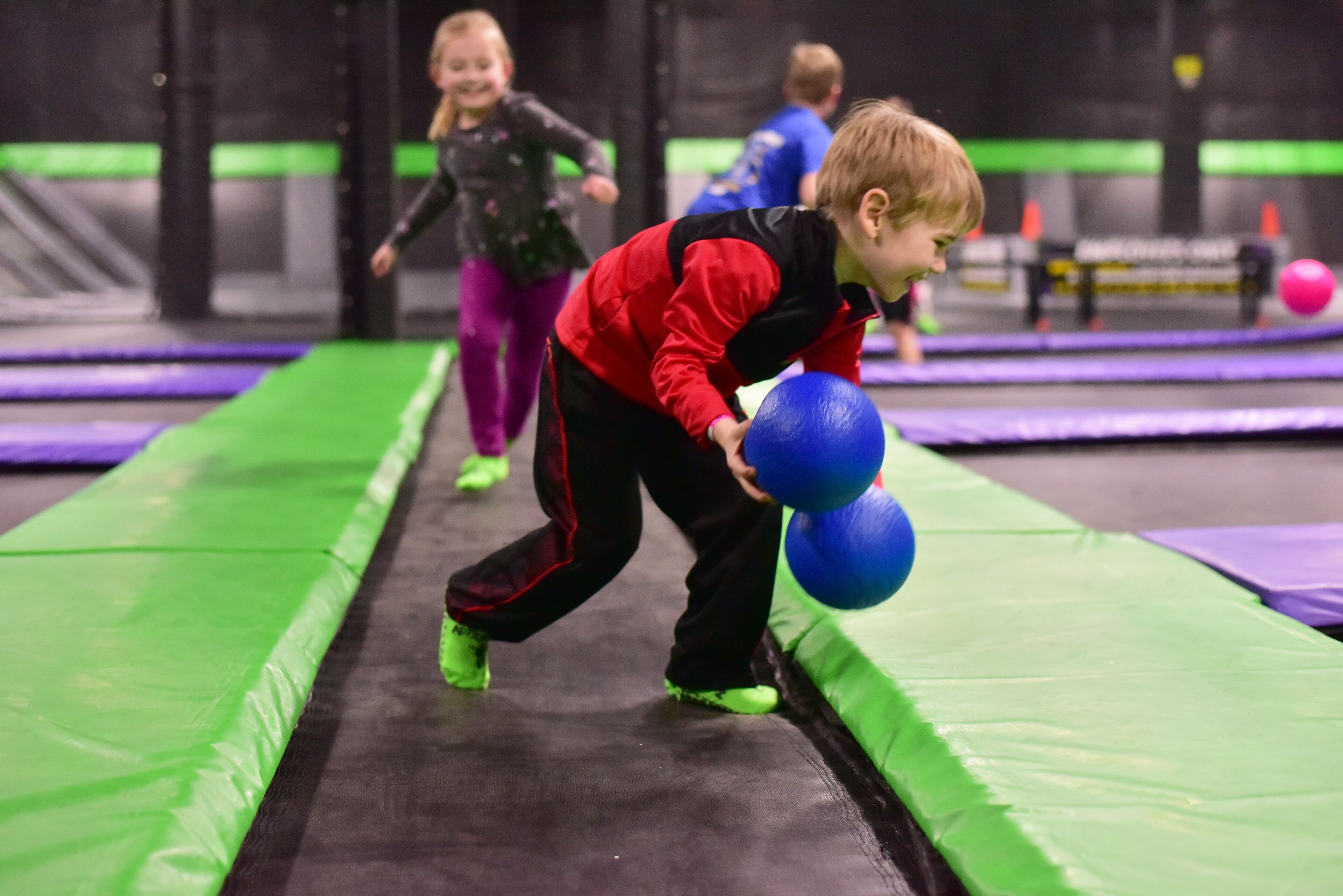 A child playing on a trampoline with a ball.