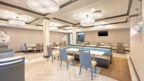 A modern hotel lobby with a herringbone floor pattern, seating areas, and a staircase leading to an upper level. - SPRINGHILL SUITES BY MARRIOTT CONYERS (Conyers)