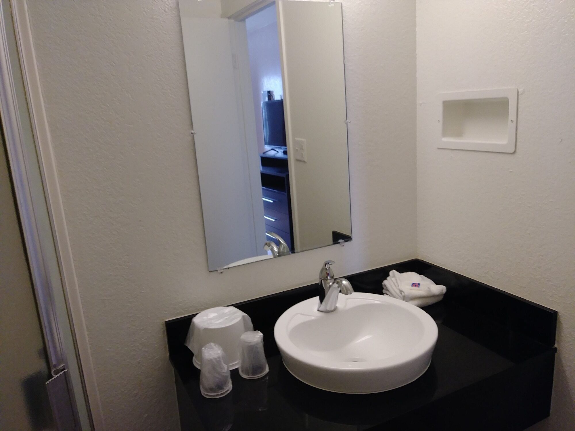 Ein Badezimmer mit Waschbecken, Spiegel und schwarzer Arbeitsplatte.
