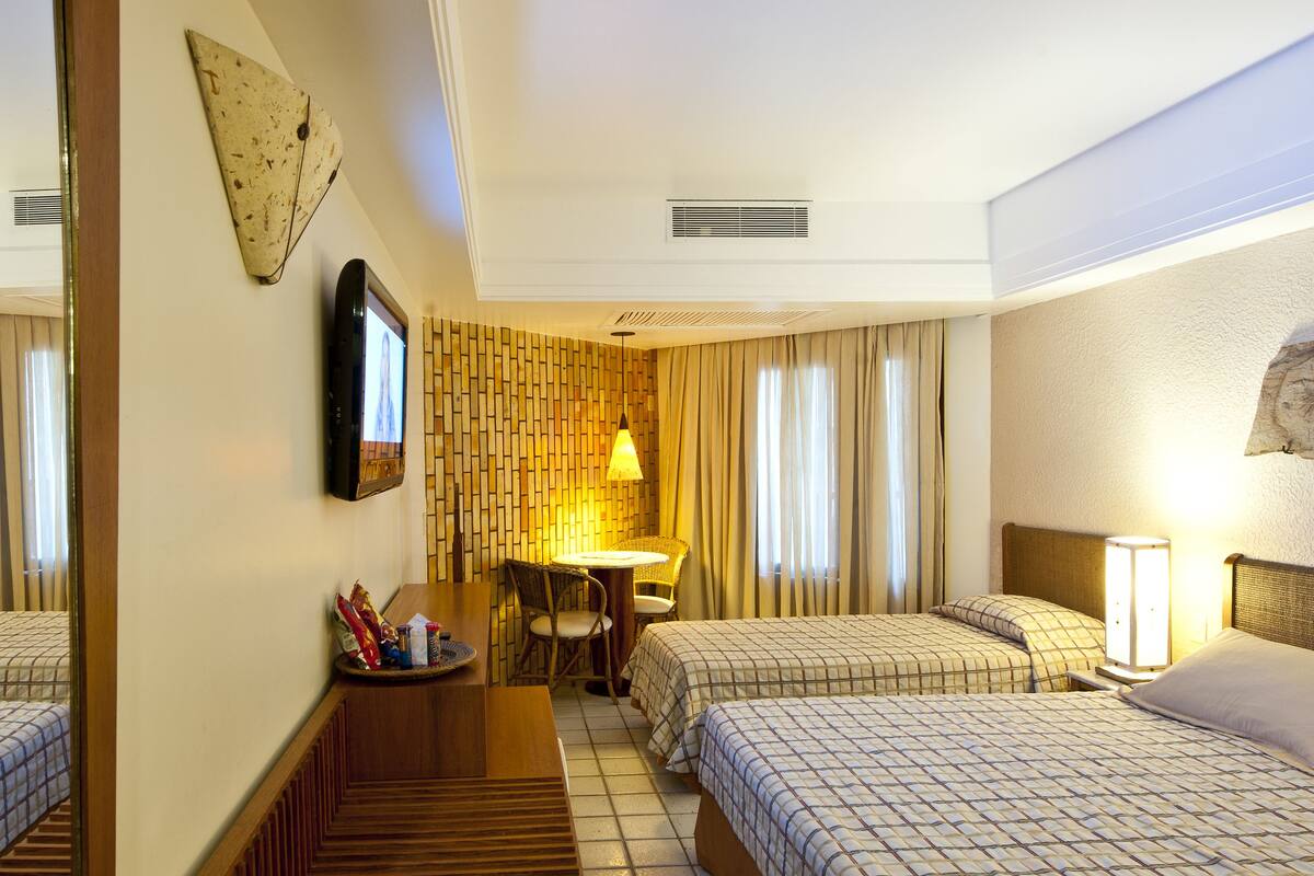 A hotel room with two beds, a small table, and a chair.