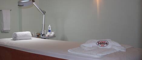 Et hotelværelse med en seng, et natbord med toiletartikler, en lampe og et håndklæde.