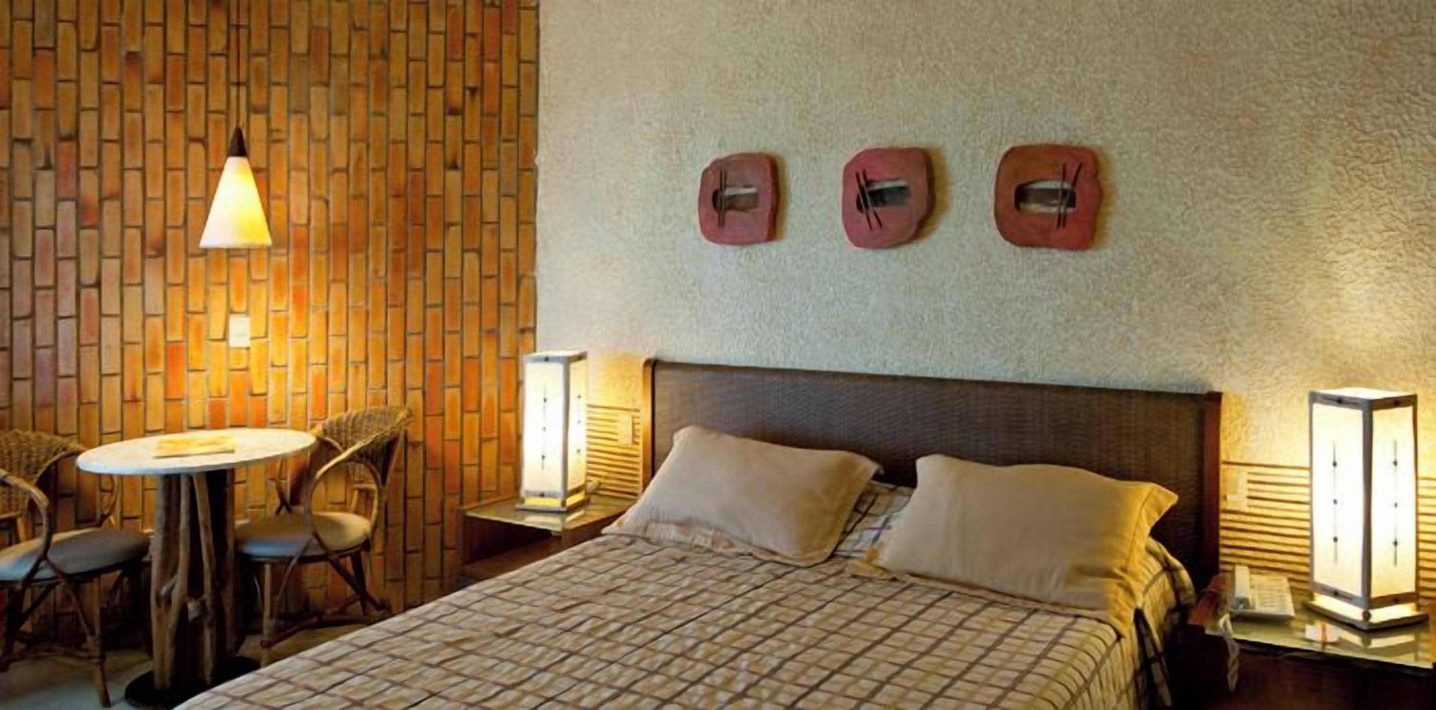 Una habitación de hotel con una cama, una mesa redonda, dos sillas y un reloj fijado a la pared.