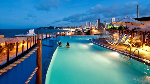 A pool area with a view of a city skyline at dusk.