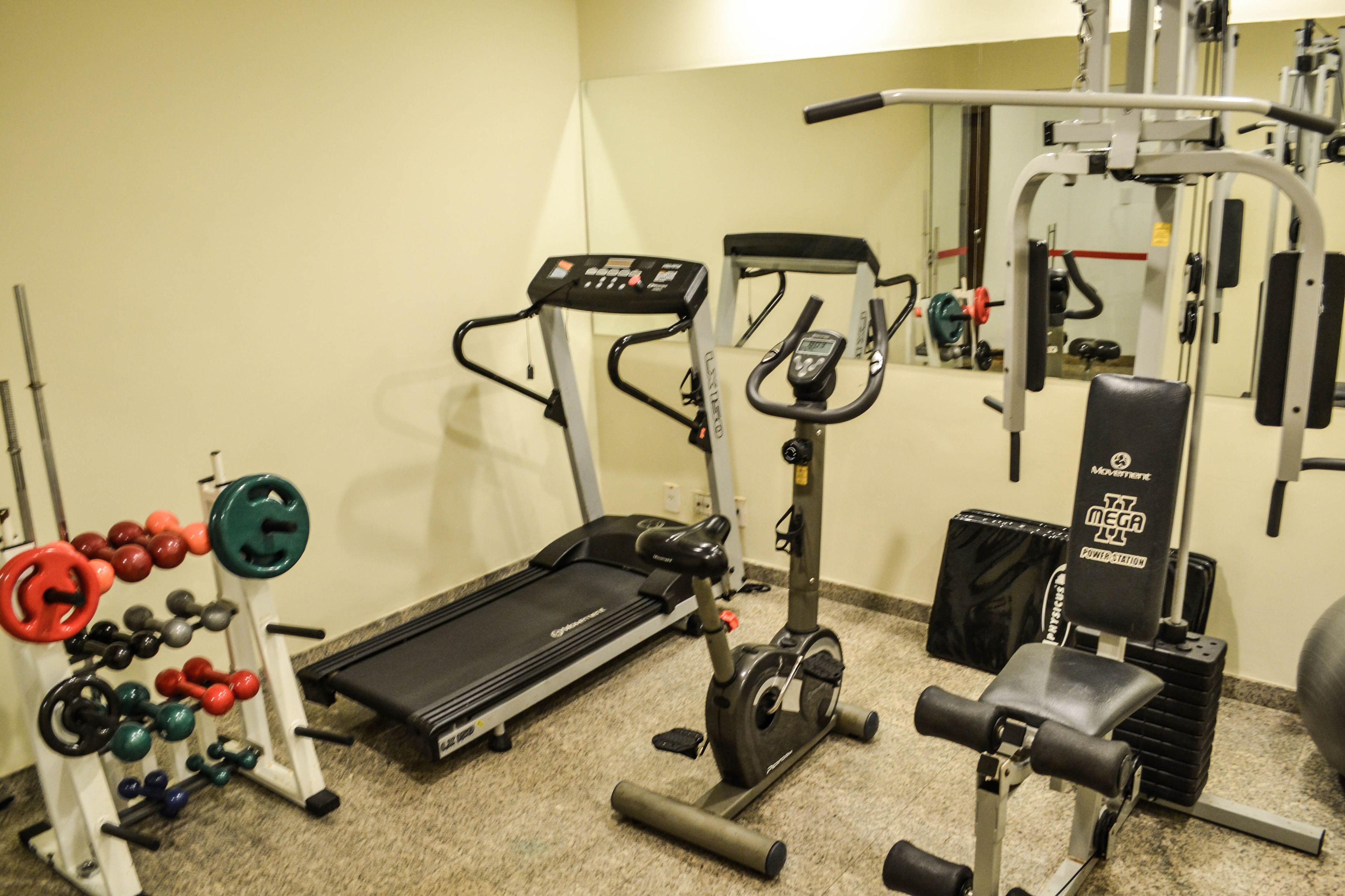 A gym with a treadmill, weight bench, and various exercise equipment.