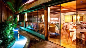An outdoor dining area with tables and chairs, a pool, and a building with large windows.