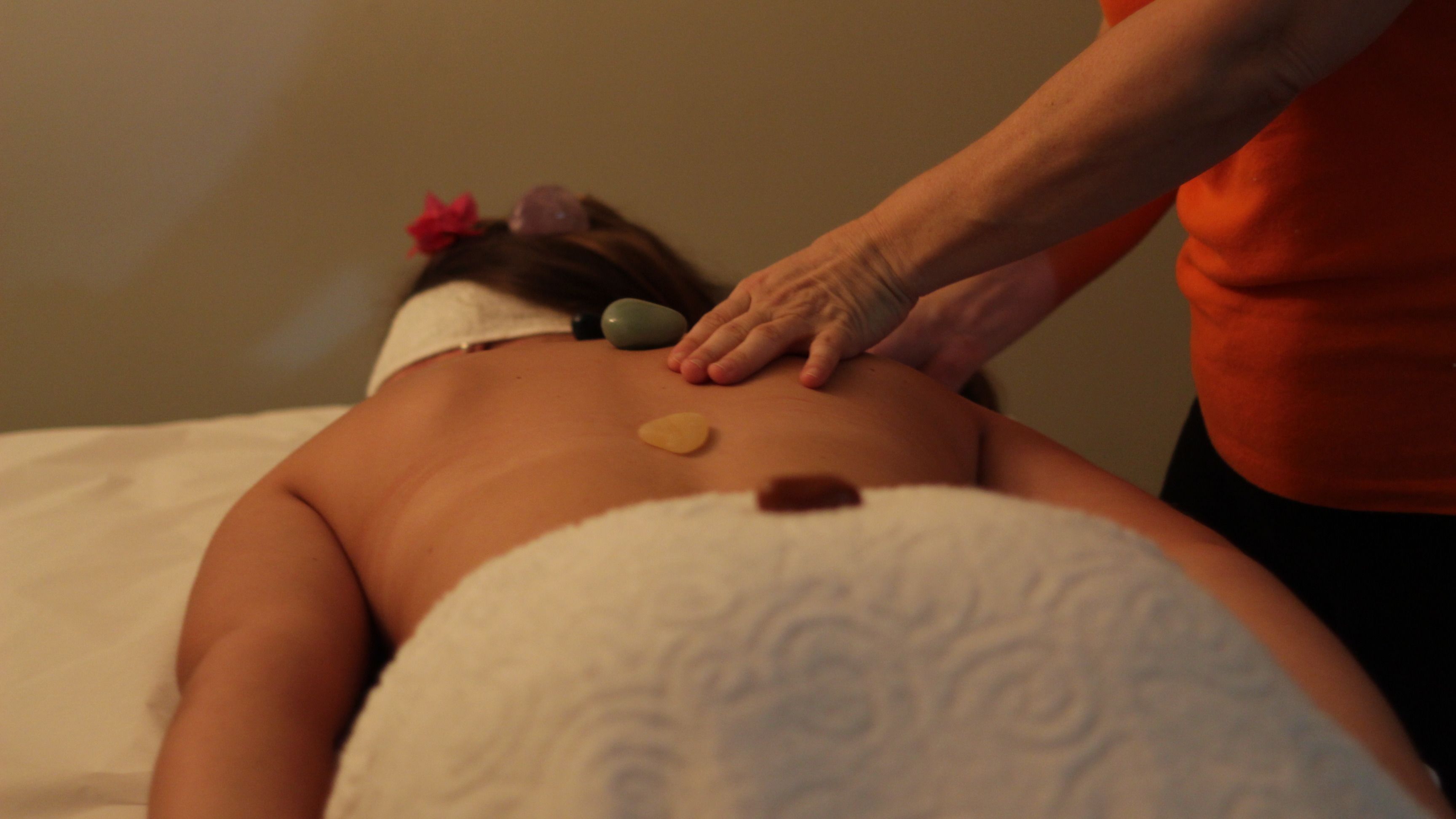 A person receiving a back massage with stones and a towel.