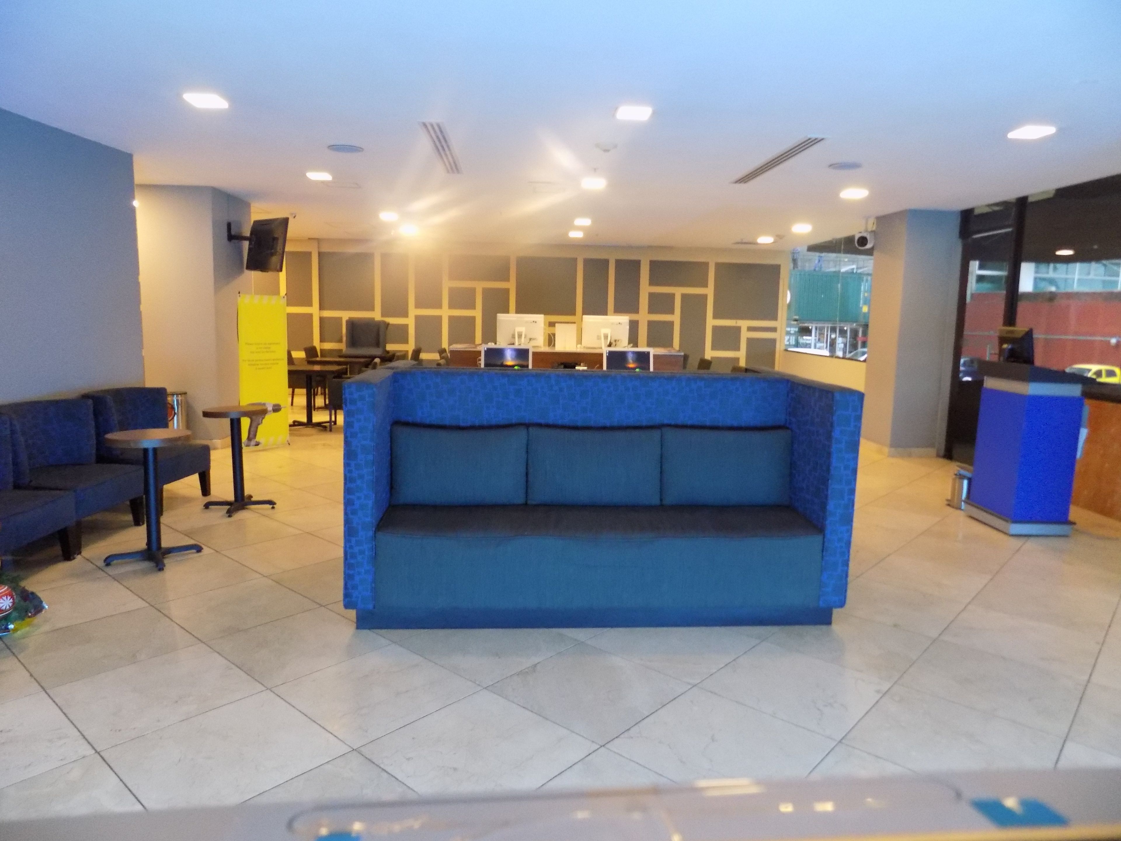 A lobby with a blue sofa, a reception desk, and a tiled floor.