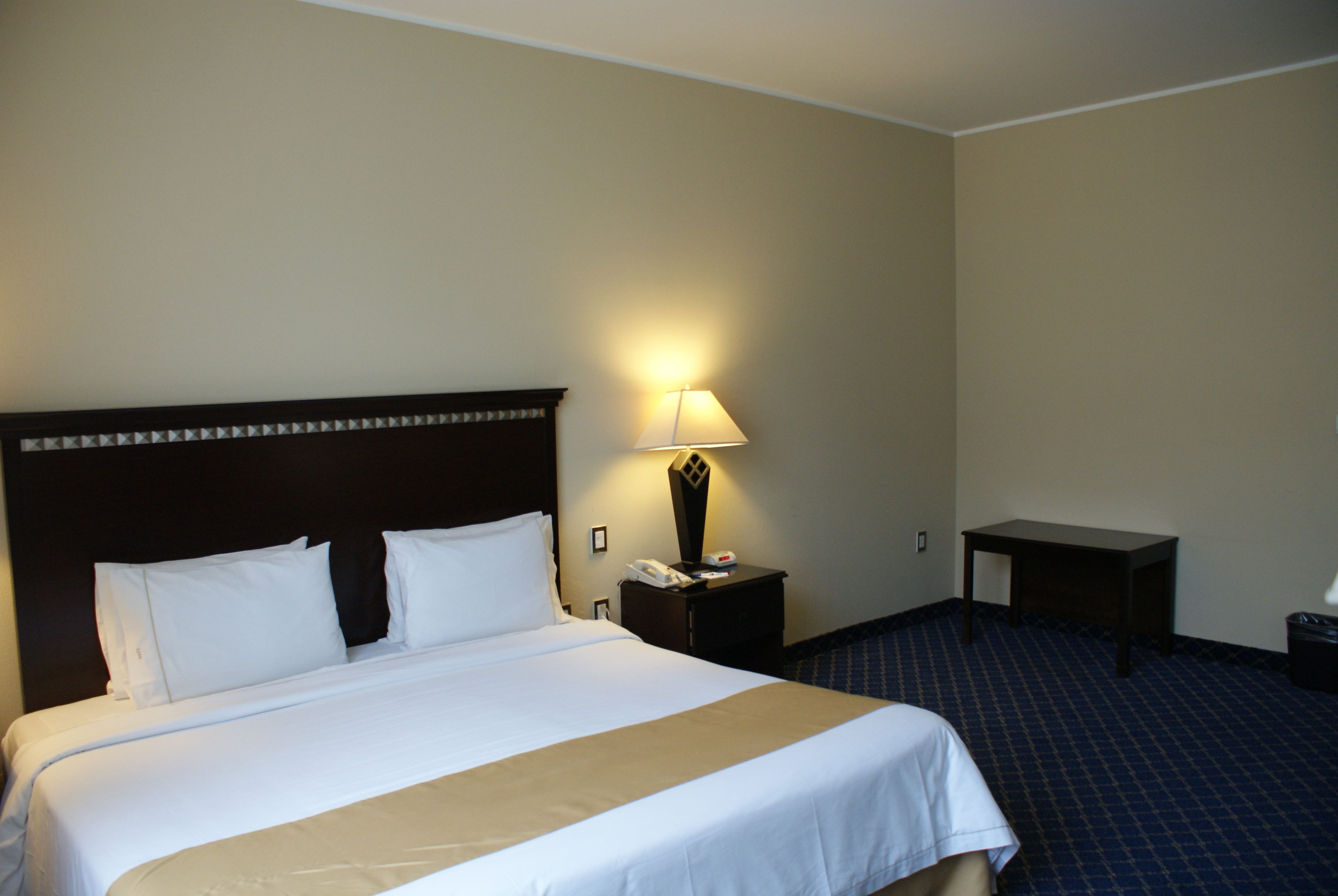 Une chambre d’hôtel avec un grand lit, une table de chevet avec une lampe et une petite table.