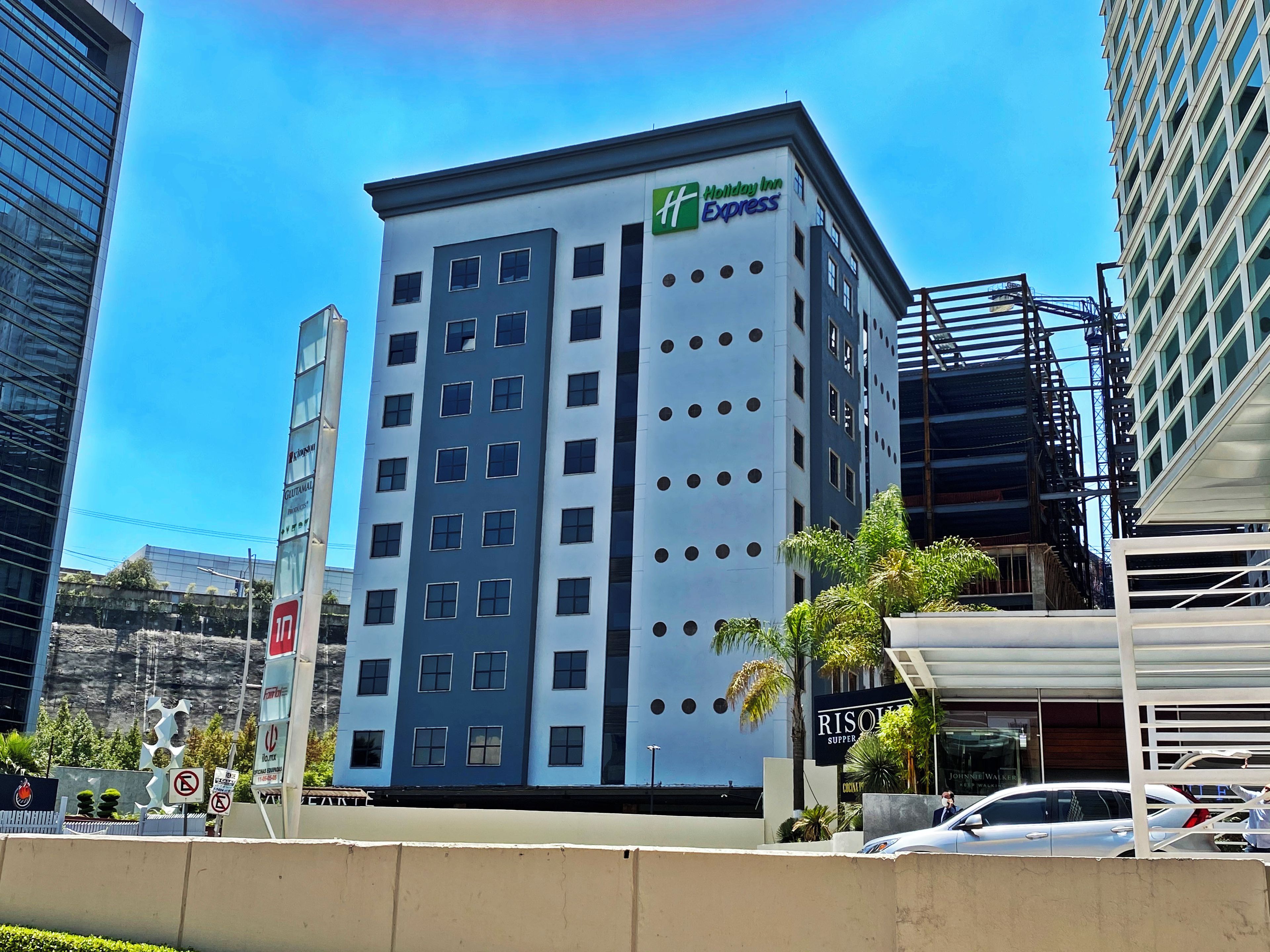 Edificio de Holiday Inn Express con diseño moderno, varios pisos y cielo despejado.