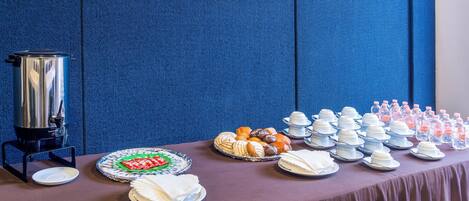 A buffet table with various food items and a beverage dispenser.