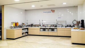 A clean, modern breakfast area with a white tiled backsplash, a variety of food dispensers, and neatly arranged plates and bowls. - Holiday Inn Express Mexico Santa Fe by IHG (Mexico City)