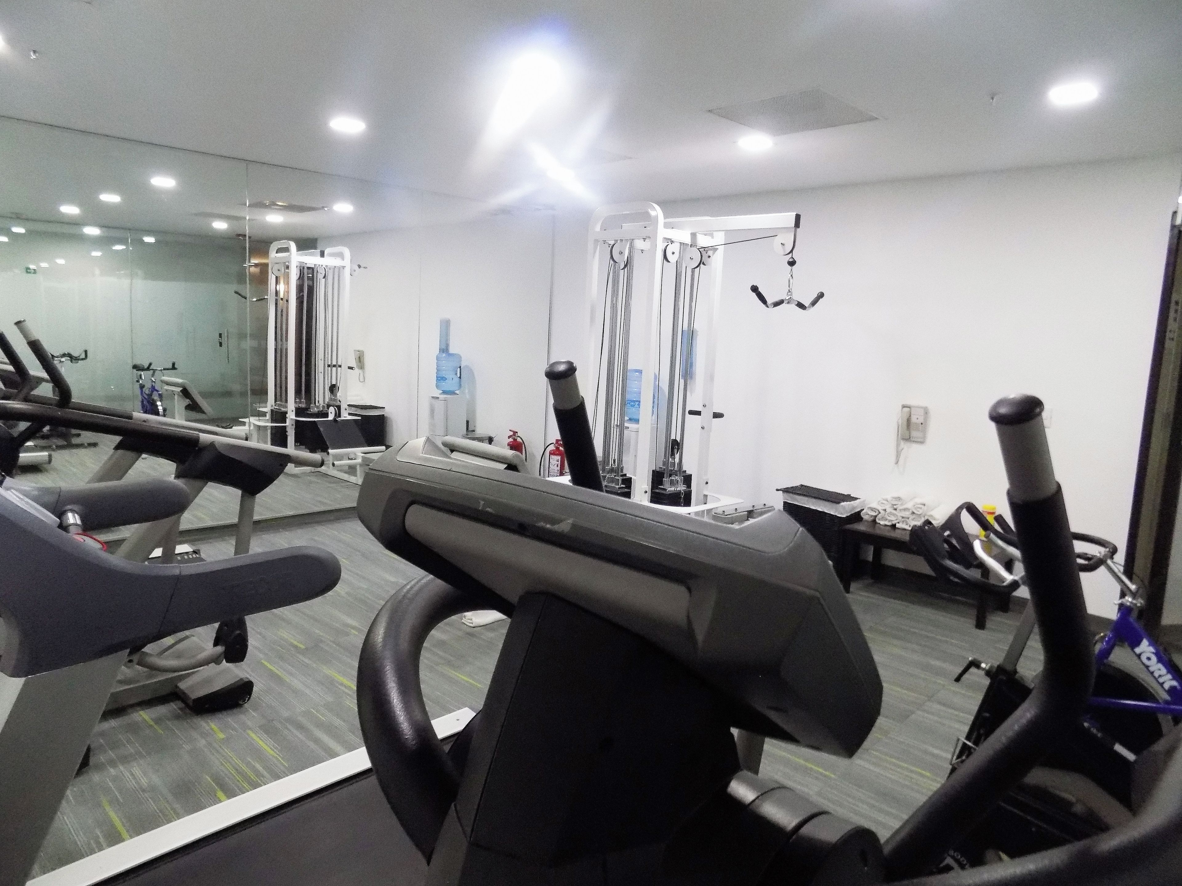 Une salle de sport équipée de matériel d’exercice, d’un distributeur d’eau et d’un miroir.
