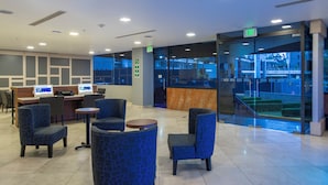 A modern lobby with seating, a reception desk, and a glass wall offering a view of the outside. - Holiday Inn Express Mexico Santa Fe by IHG (Mexico City)